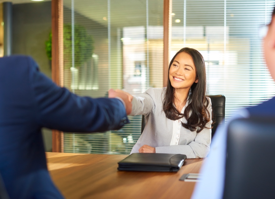  A female shacking hands with her new co-worker.